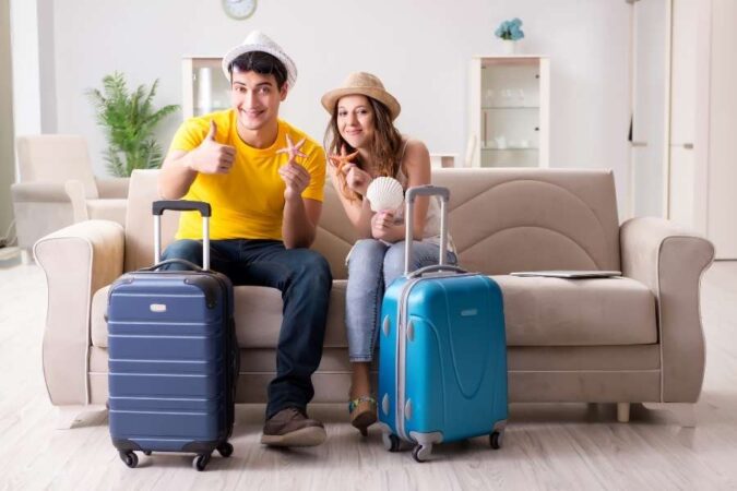 Un jeune couple avec des chapeaux de paille et leurs valises, tout excité à l'idée de commencer leurs voyages organisés.