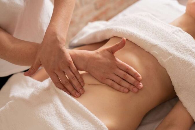 Un praticien réalise un drainage lymphatique abdominal sur une personne allongée.