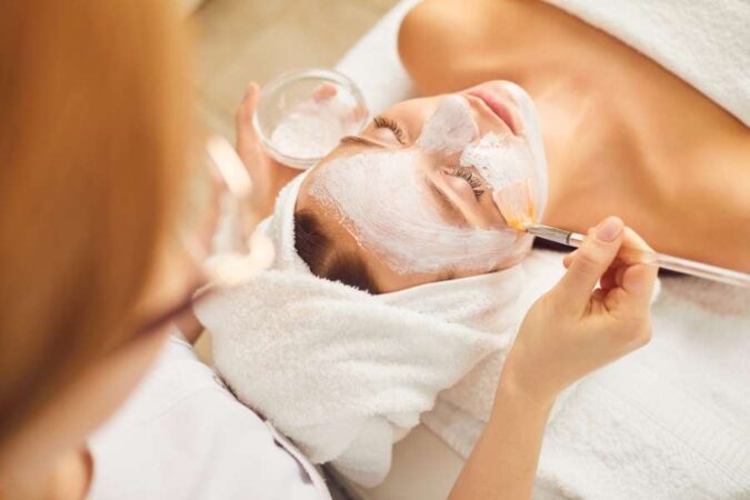 Une esthéticienne applique un masque facial lors d'un soin en institut.